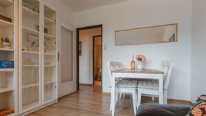 A room with a dining table, chairs, a sofa, and a large open cabinet. - Apartment Smilla by Interhome (Bad Gastein)