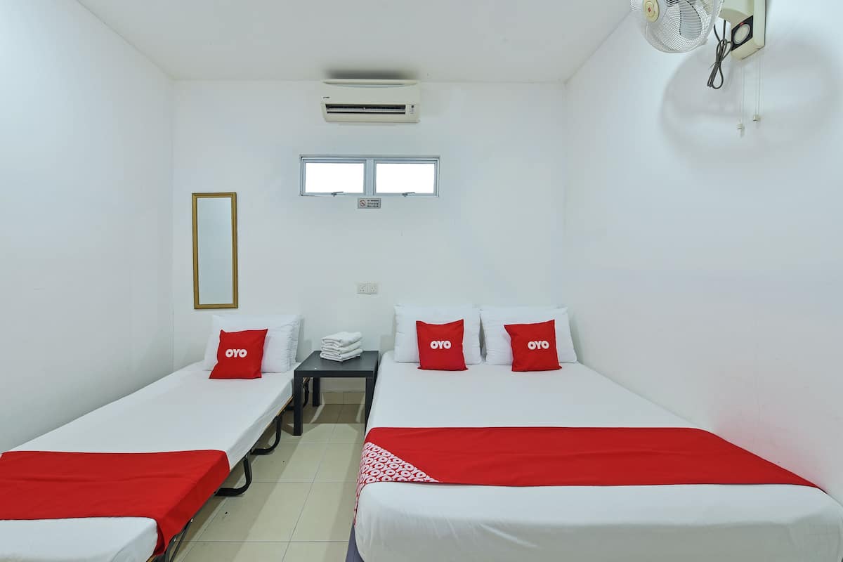 A small, clean room with two single beds, a desk, a chair, and a window.