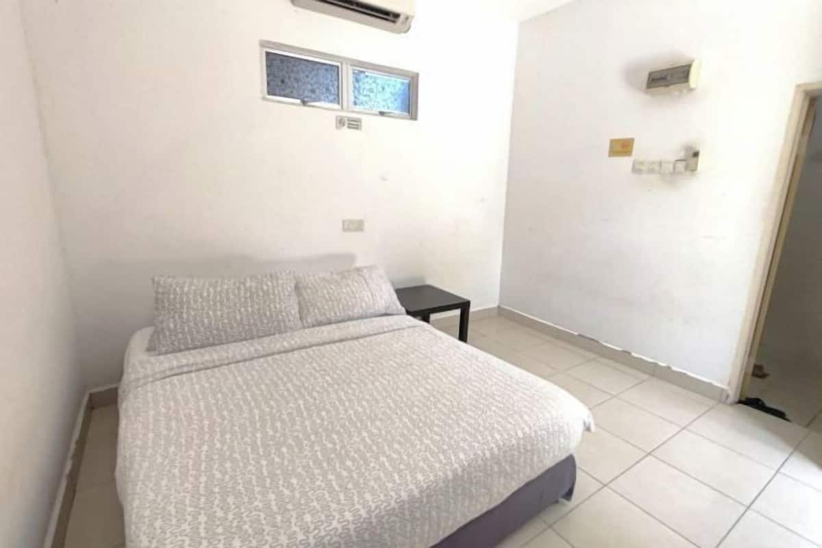 A bedroom with a bed, a small table, and a wall-mounted air conditioner.