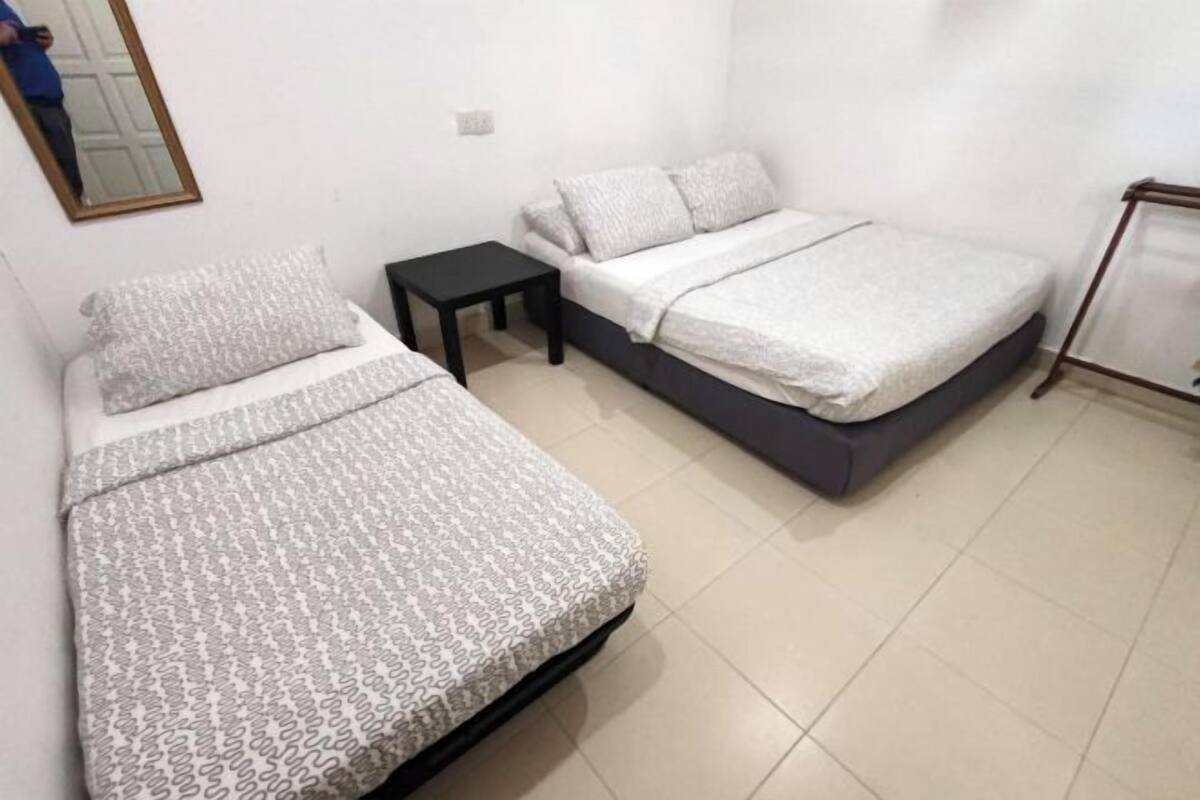 A small, clean room with two beds, a small table, and a mirror on the wall.