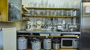 Una cocina con electrodomésticos de acero inoxidable, estantes con recipientes de vidrio, utensilios colgantes y ollas de metal.