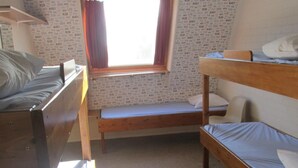 Un dormitorio con literas, una ventana pequeña y una pared cubierta de mensajes.
