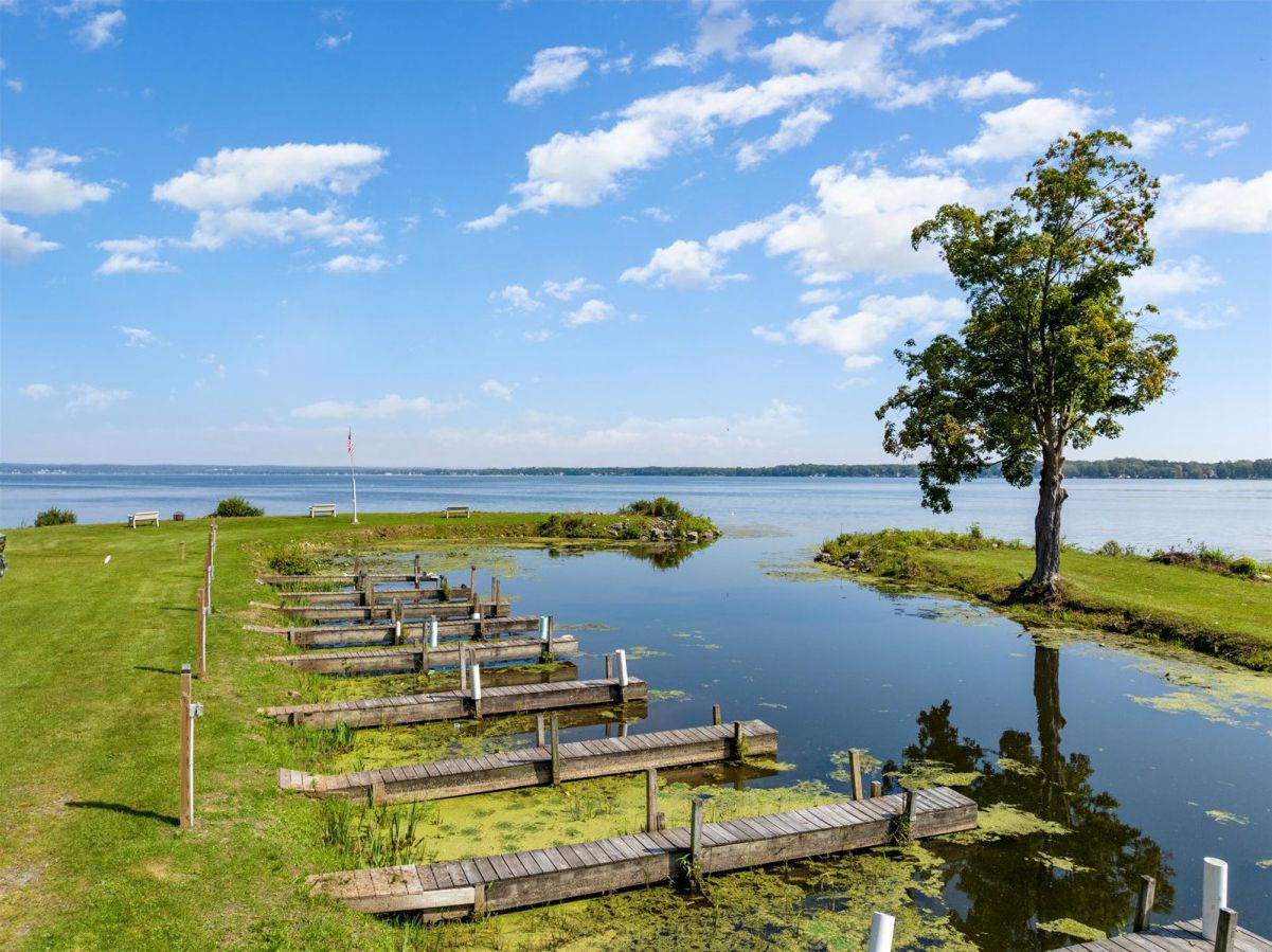 Ein ruhiger See mit Holzanlegestellen, grünen Ufern und einem Baum.
