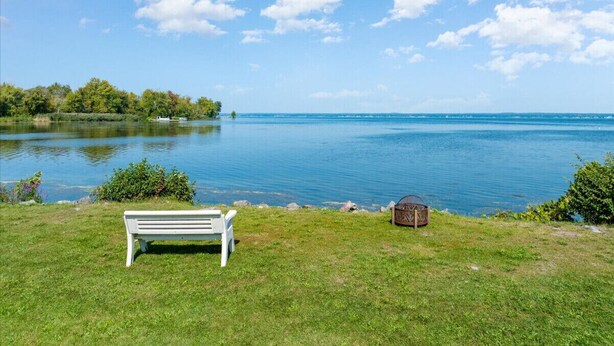 Blick auf einen See mit einer weißen Bank und einem kleinen Holzgebäude.