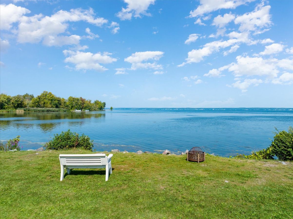 A lakeside view with a white bench and a small wooden structure.