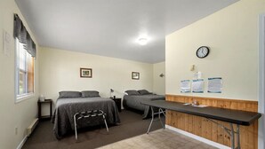 Ein Zimmer mit zwei Betten, einem Schreibtisch, einer Uhr und einigen Dokumenten an der Wand.