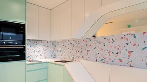 Una cocina moderna con horno empotrado, un lavamanos y un banco blanco.