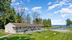 A motel with a single-story structure, outdoor seating, and a view of a body of water. - Hidden Harbor Marina, The Entire Property (Sleeps 16) - Oneida Lake's Premier Fishing Getaway (Canastota)
