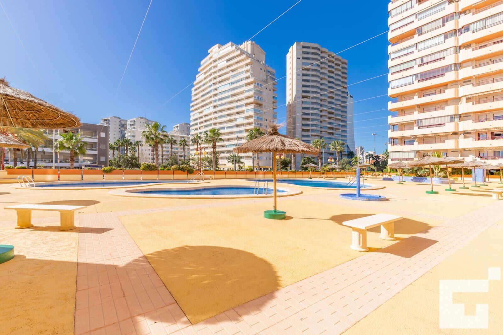 A resort pool area with multiple pools, lounge chairs, and umbrellas.