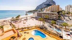 Ett semesterhotell med pool, strand och utsikt över bergen.