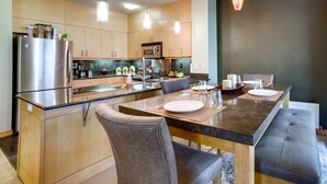 Une cuisine moderne dotée d’un îlot central, d’appareils électroménagers en acier inoxydable et d’un coin repas avec une banquette.