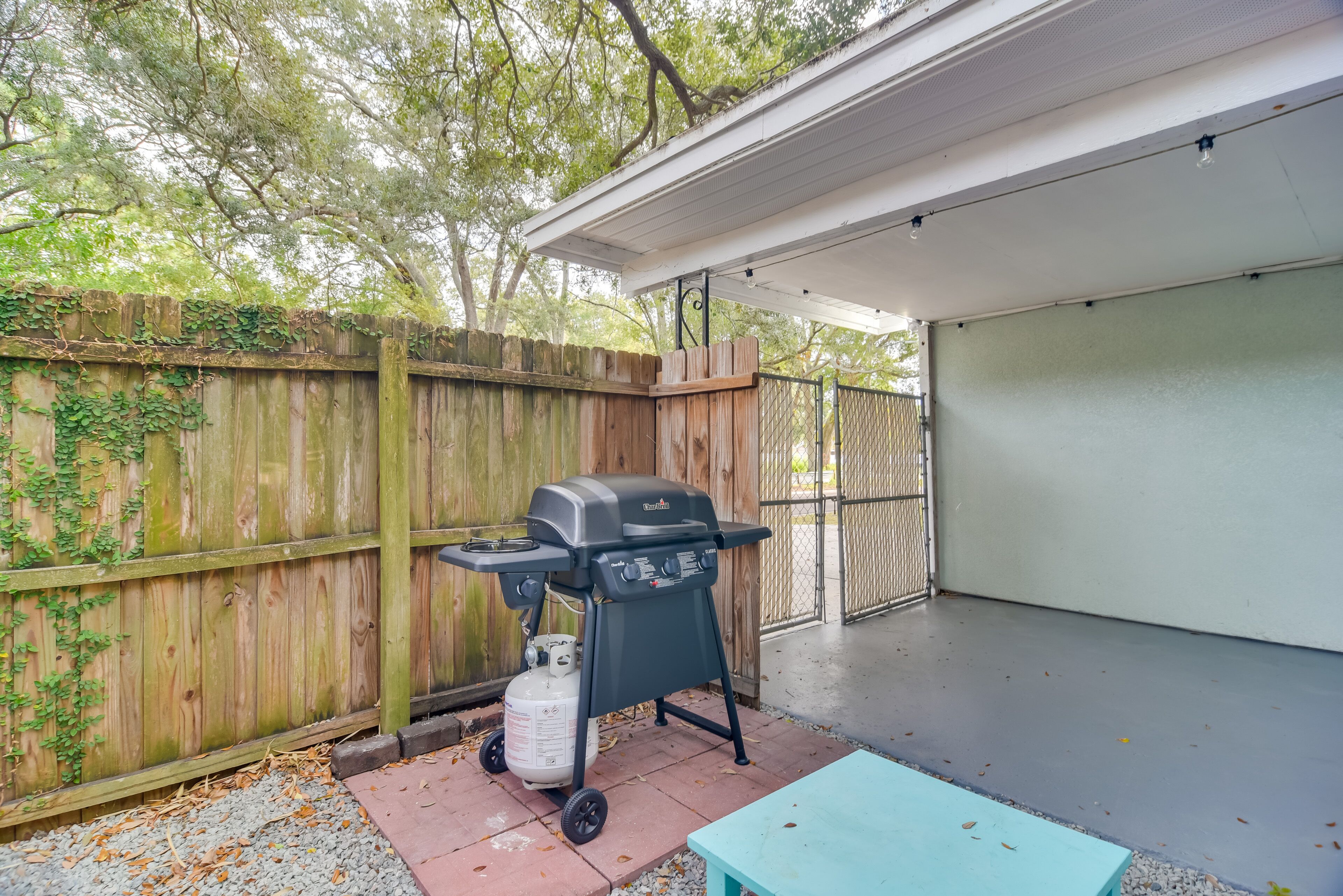A backyard with a barbecue grill, a table, and a covered patio area.