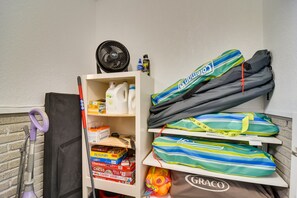 Un espace de rangement contenant des produits de nettoyage, un aspirateur et plusieurs sacs de couleurs vives.