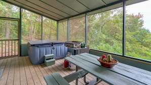 A covered outdoor area with a hot tub, a table with a cactus, and a view of trees. - Mountaintop Ellijay Cabin w/ Private Hot Tub (Ellijay)