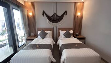 A hotel room with two beds, a large window, and a view of the outside.
