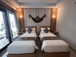 A hotel room with two beds, a large window, and a view of the outside.