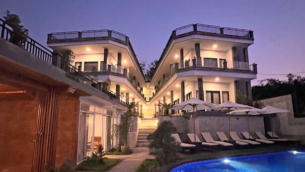 Un hotel moderno y espacioso con un patio central, piscina y varios balcones.