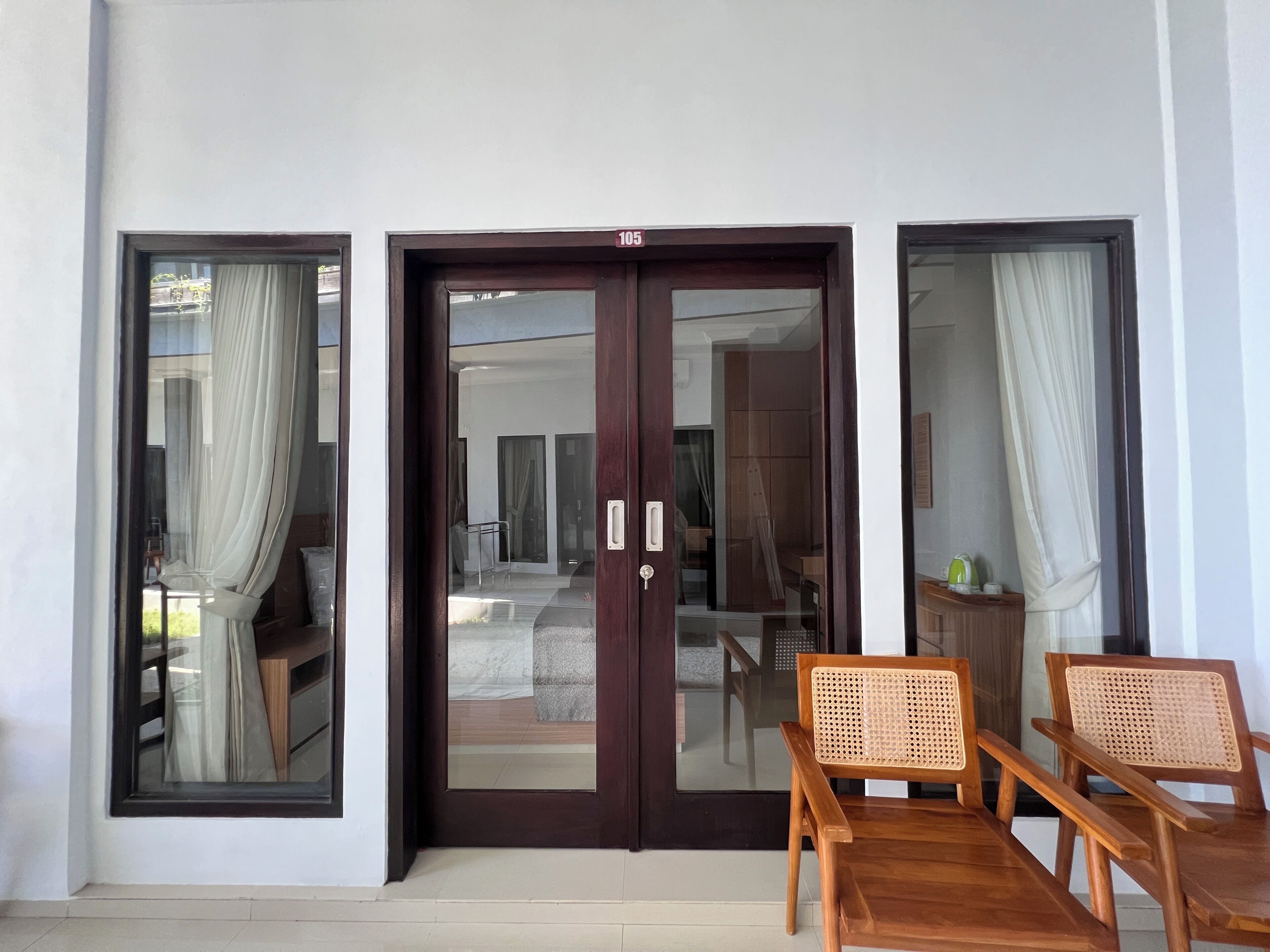 A room with a sliding glass door, a wooden table with two chairs, and a view of an interior space through the door.