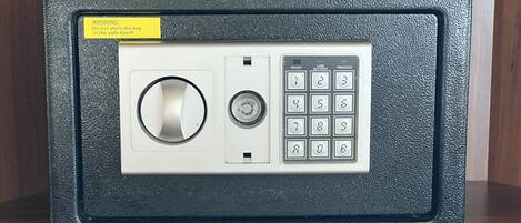 A safe with a keypad and a keyhole, a warning label, and a small set of keys on top.