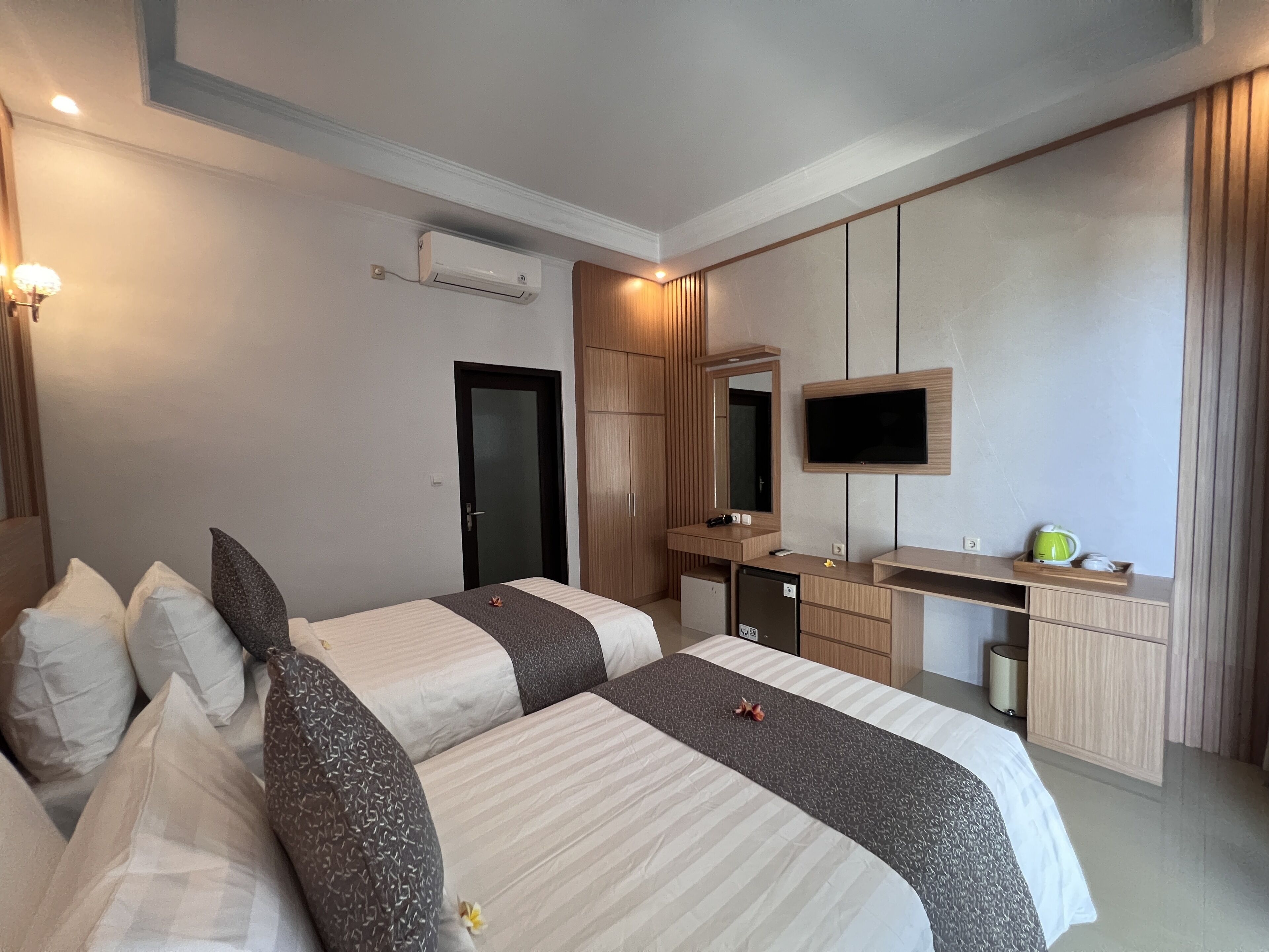 Quarto de hotel moderno com uma cama grande, uma escrivaninha, uma televisão e um guarda-roupa.