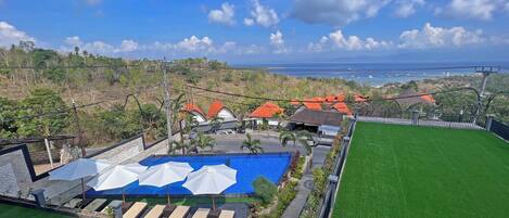 A resort with a pool area, lounge chairs, and a view of the ocean.