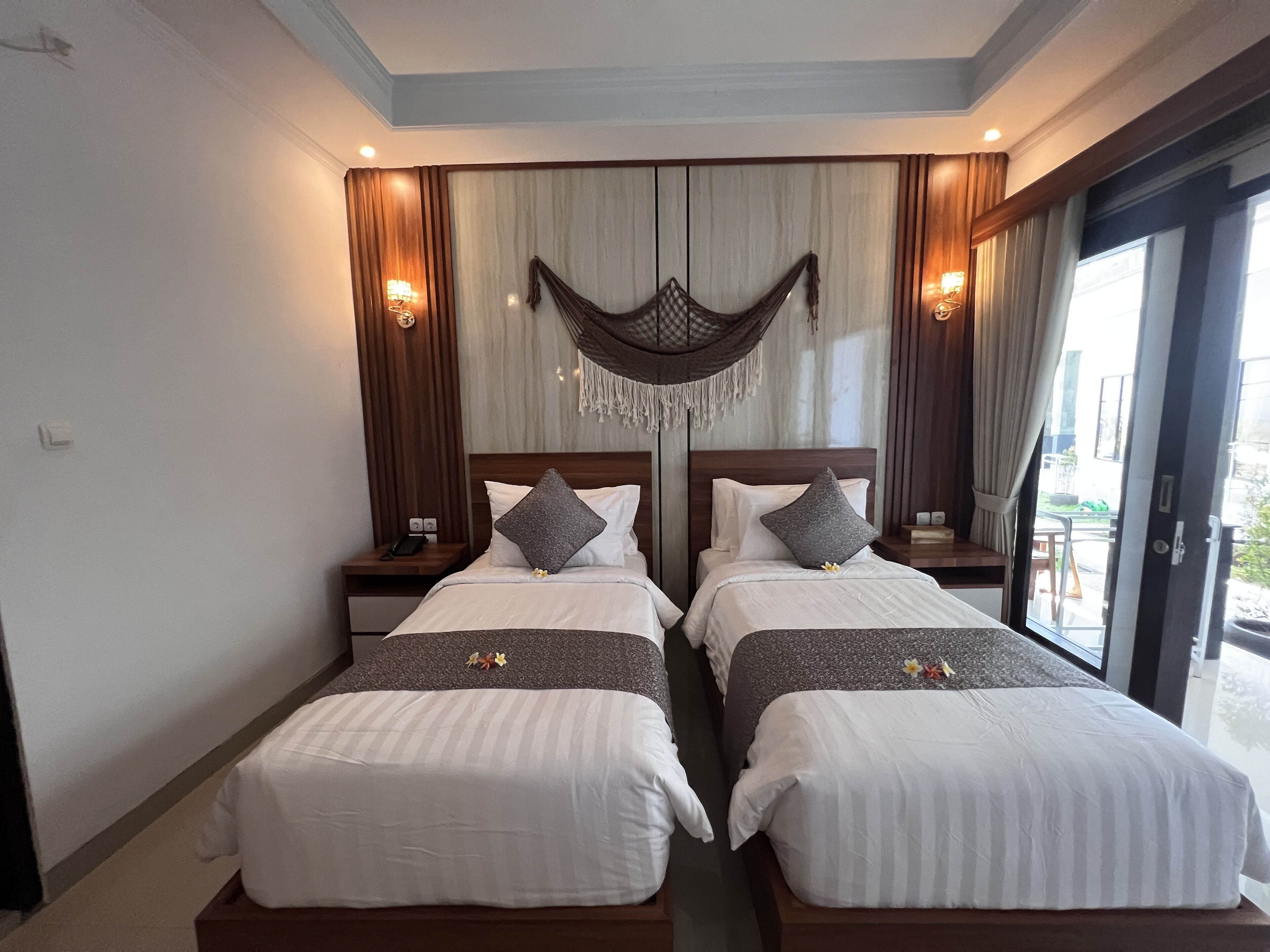 A hotel room with two beds, a large window, and a balcony.
