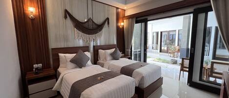 A hotel room with two beds, a large window, and a view of the outdoor area.