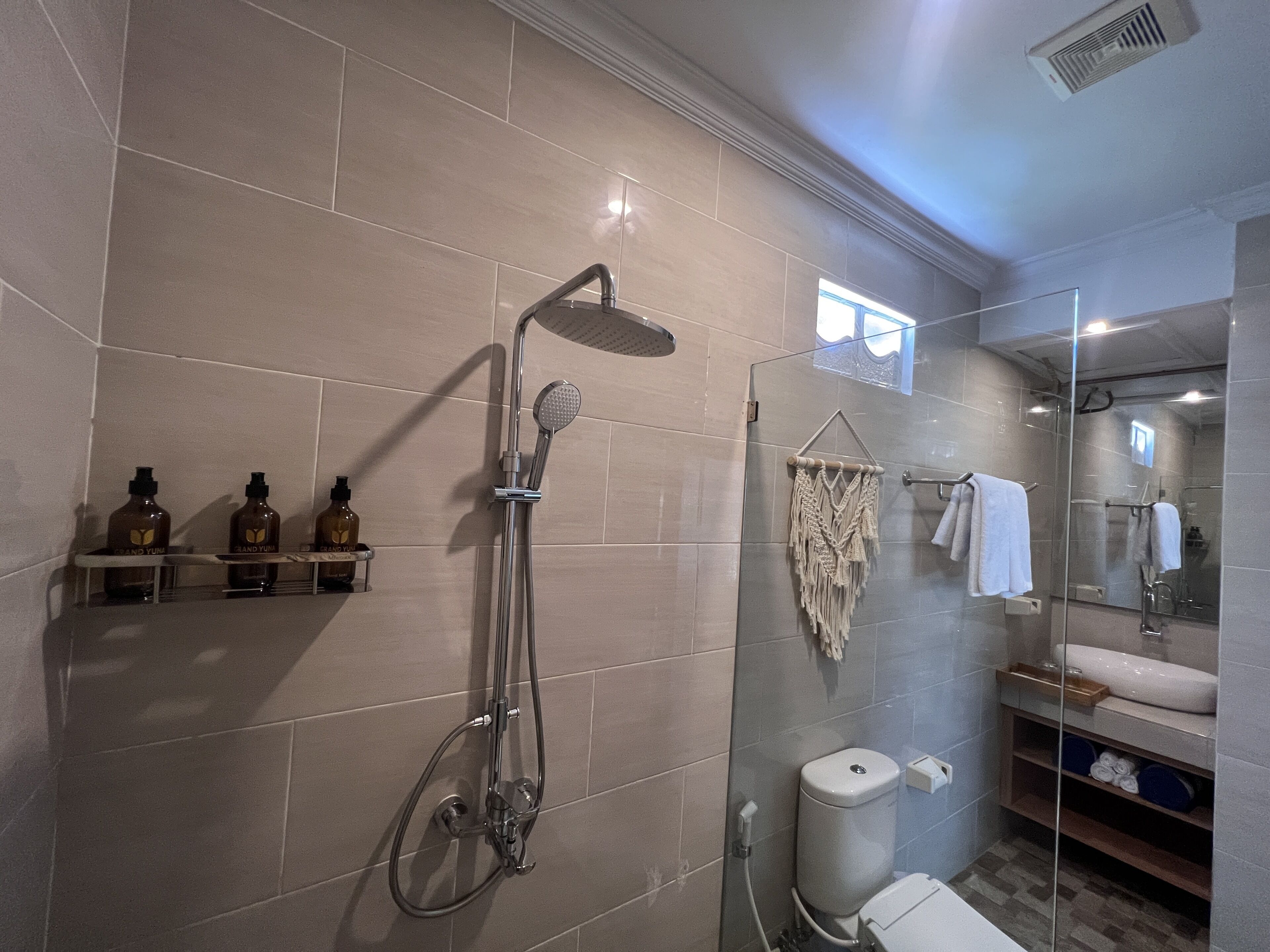 Uma casa de banho moderna com cabine de duche em vidro, sanita e toucador com lavatório e espelho.