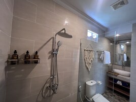 Uma casa de banho moderna com cabine de duche em vidro, sanita e toucador com lavatório e espelho.