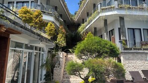 Un hotel con un patio central, piscina y balcones con vegetación.