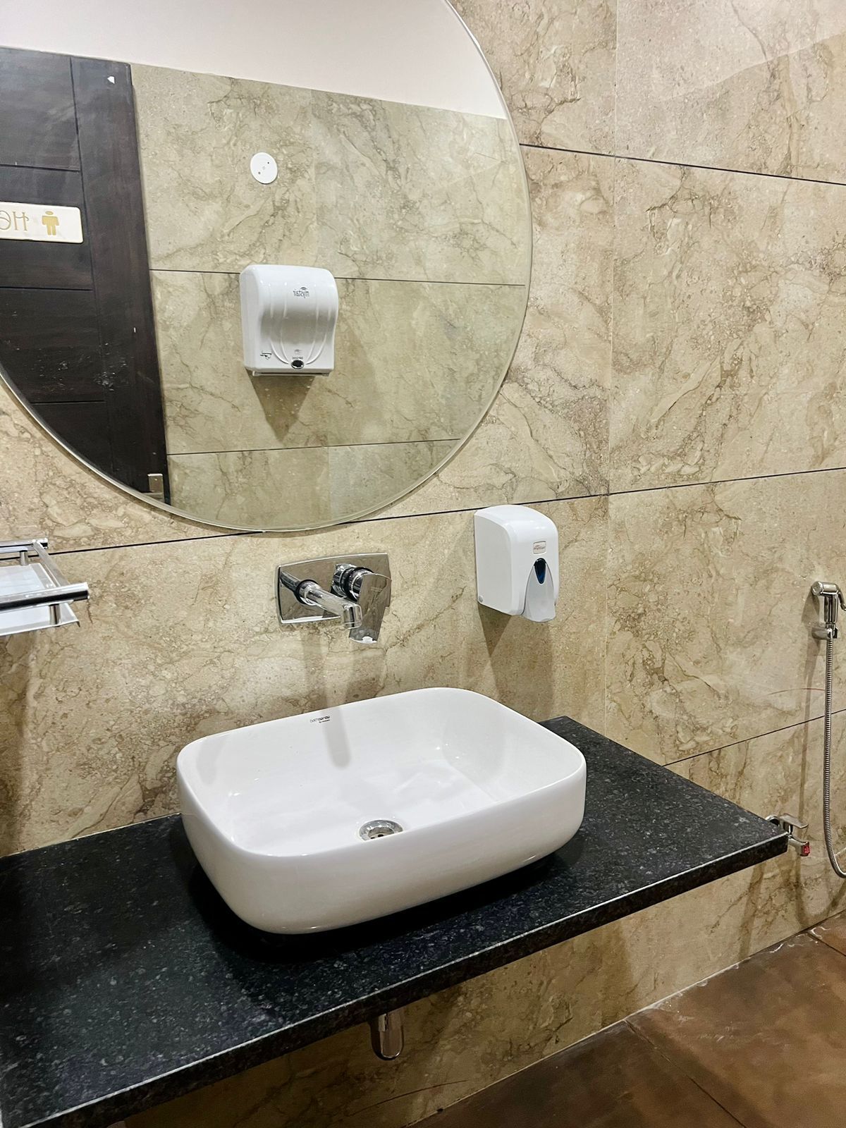A bathroom with a white sink, a mirror, and two paper towel dispensers.