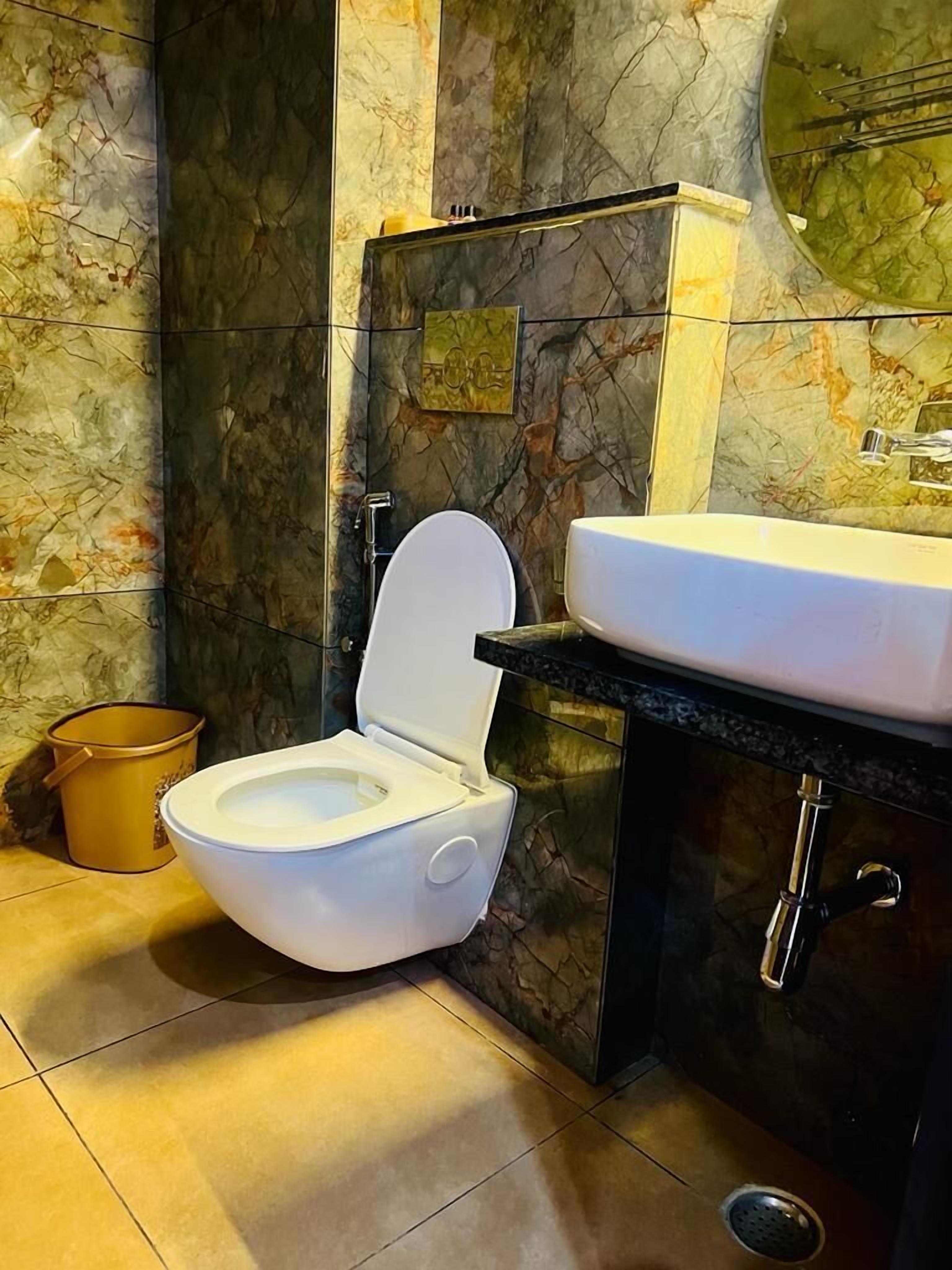 Un bagno con un water bianco, un lavandino e uno schienale in marmo.
