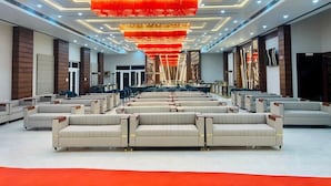 A spacious lobby with rows of seating, a large chandelier, and a modern ceiling design. - R G Bilkha Hotel And Resorts (Alwar)