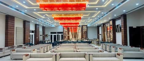 A spacious lobby with rows of seating, a large chandelier, and a modern ceiling design.