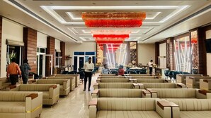 A spacious hotel lobby with rows of beige sofas and a red decorative ceiling. - R G Bilkha Hotel And Resorts (Alwar)