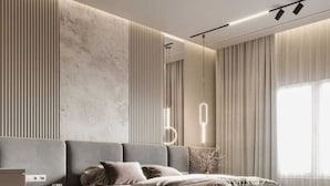 A modern bedroom with a large bed, a bedside table, a lamp, and a wall-mounted light fixture. - R G Bilkha Hotel And Resorts (Alwar)