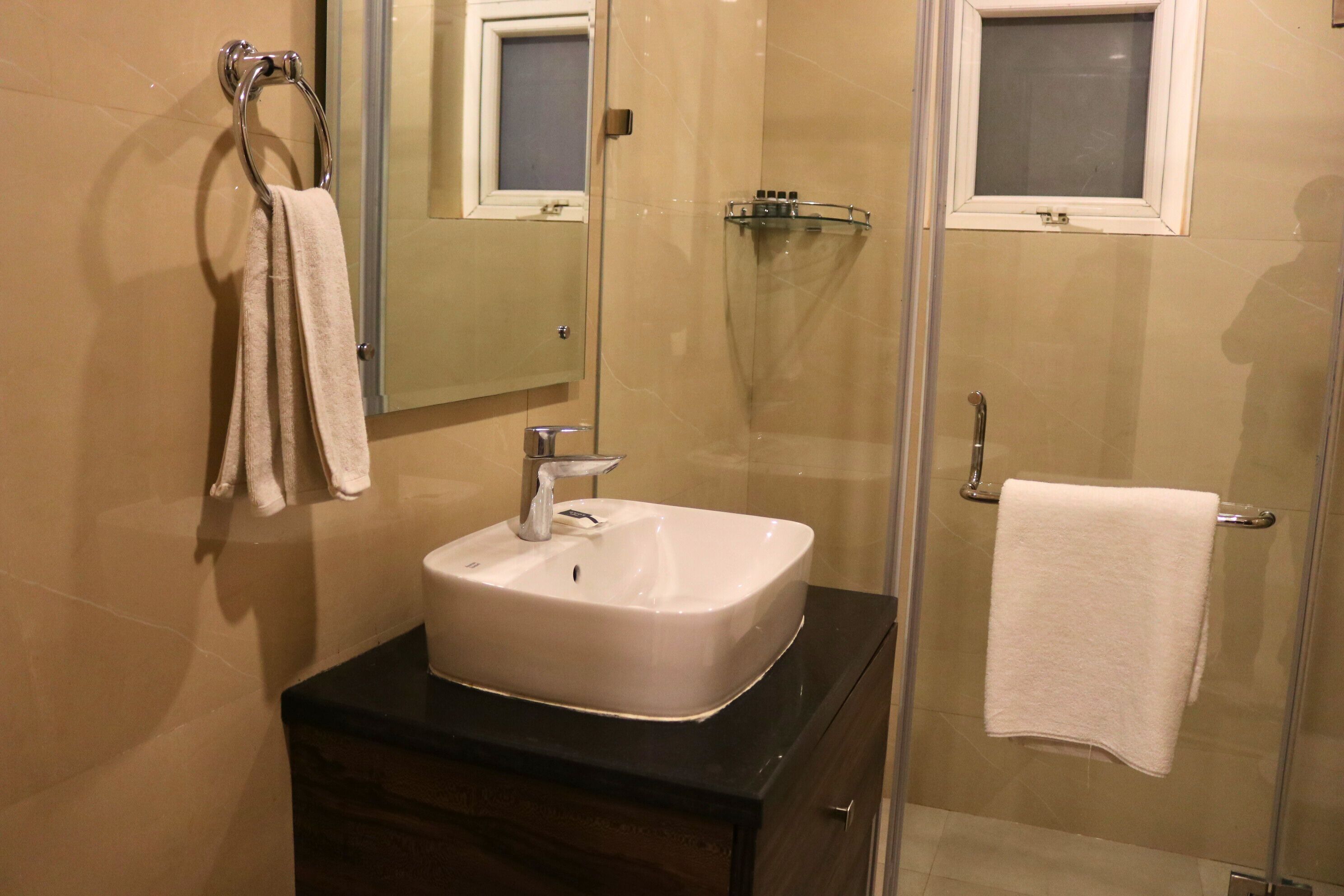 A modern bathroom with a white sink, a glass shower enclosure, and a mirror above the sink.