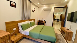 A hotel room with a wooden bed, a desk, a chair, a TV, and a mirror.