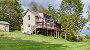 A two-story house with a balcony and a covered porch. - Charming Putney Home: Porch, Grill & Hiking Trails (Putney)