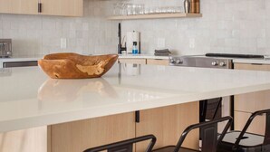 Une cuisine moderne dotée d’un grand îlot central, de meubles en bois et d’un luminaire suspendu noir.
