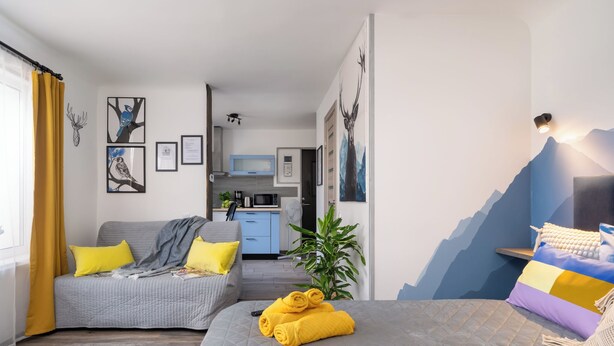 A modern hotel room with a bed, a sofa, a dining area, and a kitchen in the background. - Lovely Scandinavian style studio in Riga (Rīga)