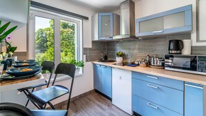 A modern kitchen with blue cabinets, a microwave, and a coffee maker. - Lovely Scandinavian style studio in Riga (Rīga)