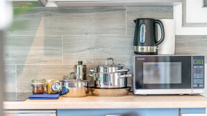 A kitchen with a microwave, kettle, and various pots and jars on the counter. - Lovely Scandinavian style studio in Riga (Rīga)