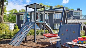 A playground with climbing structures and a slide, surrounded by trees and a building in the background. - Lovely Scandinavian style studio in Riga (Rīga)