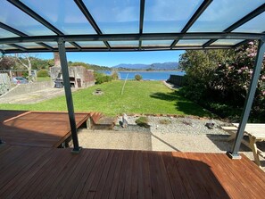 A covered outdoor area with a wooden deck, a view of a lake, and a picnic table.