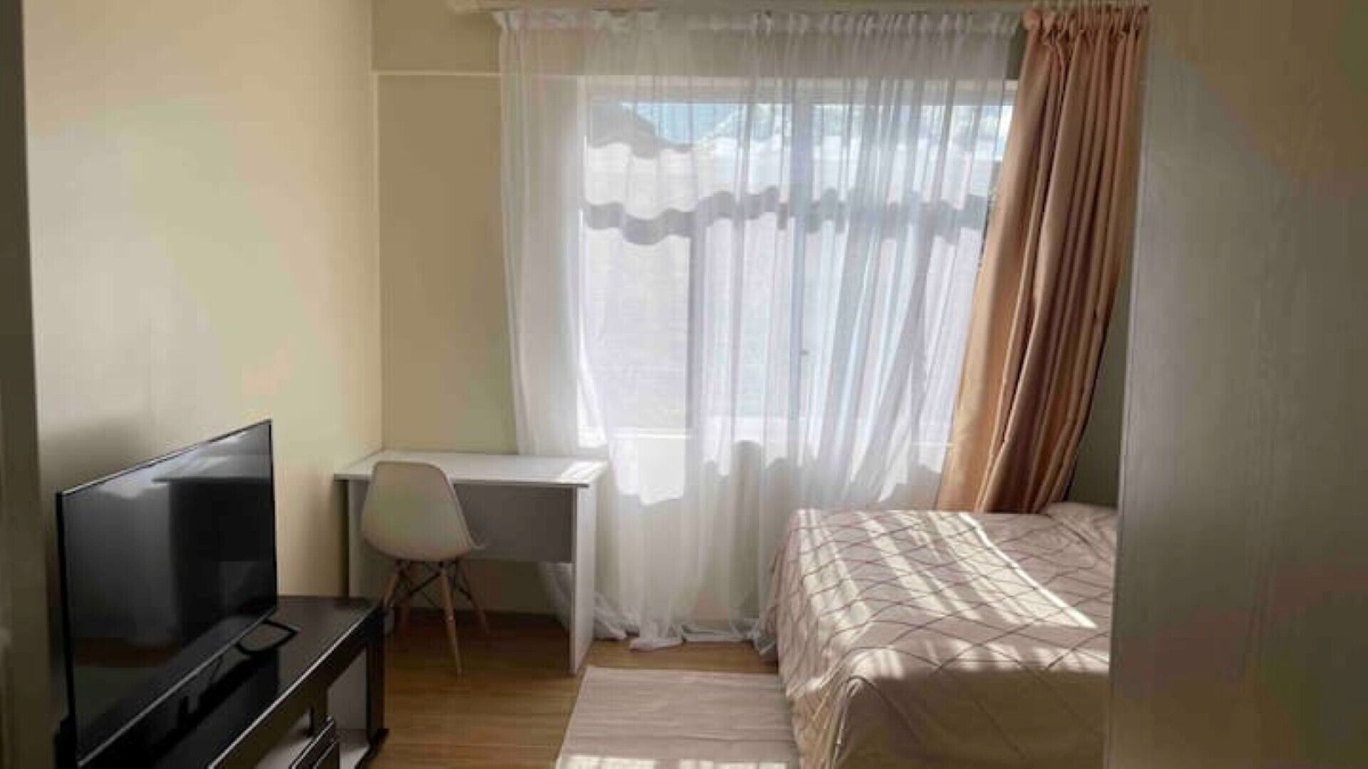 Une chambre à coucher comprenant un lit, un bureau, une chaise et un téléviseur.