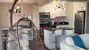 Una cocina moderna con una isla central, un sillón colgante y un sofá.