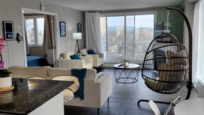 Una sala de estar moderna con sofá, sillas, una mecedora colgante, una mesita y vistas al exterior.
