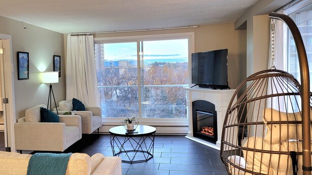 Una sala de estar moderna con un sofá, sillones, una mesita, chimenea y televisor.