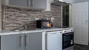 A compact kitchen with a built-in microwave, a sink, and a dishwasher. - Elegant Studio: Studio Suite 5 (Coventry)